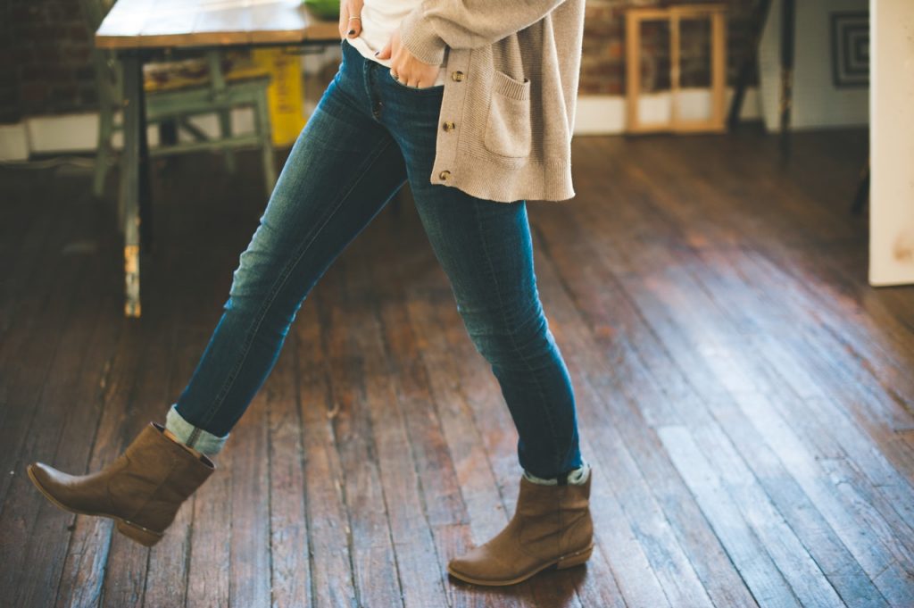 femme portant un jean un gilet long beige un haut blanc et des bottines marron