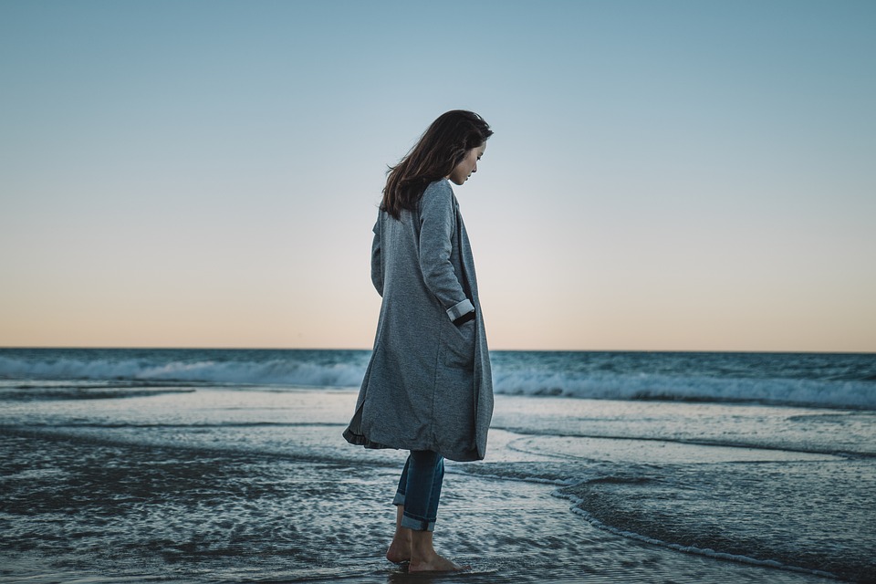 Femme en veste d'hiver face à la plage