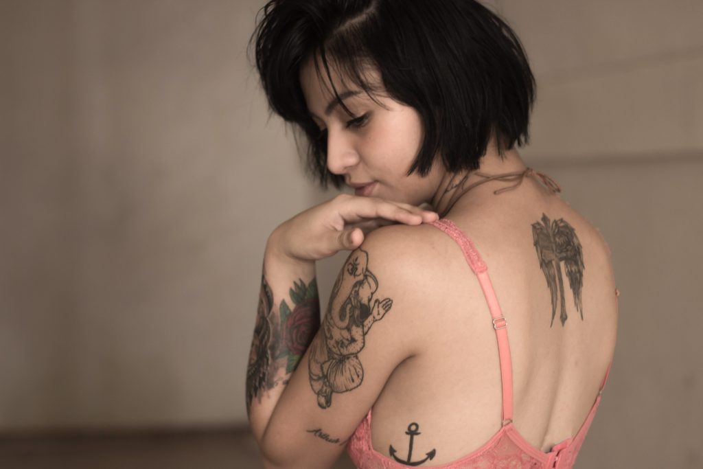 Une femme avec des tatouages qui porte un soutizn-gorge rose