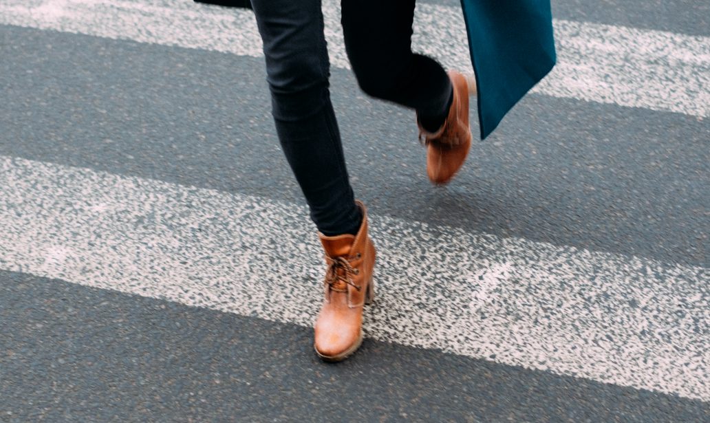 femme portant un manteau long un pull clair un jean foncé et des bottines marron